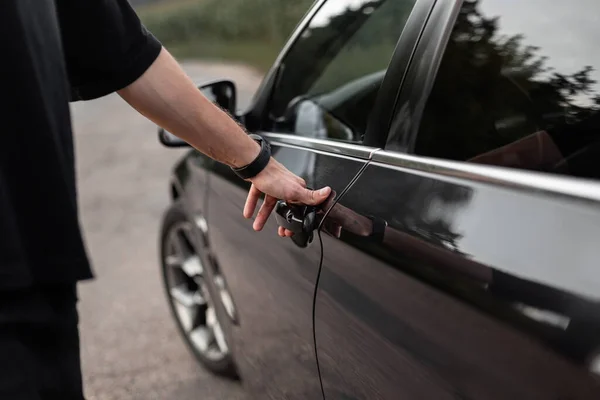 男の運転手が黒い車のドアを開ける 男の手はドアのハンドルを握る クローズアップ レンタカーを借りる — ストック写真