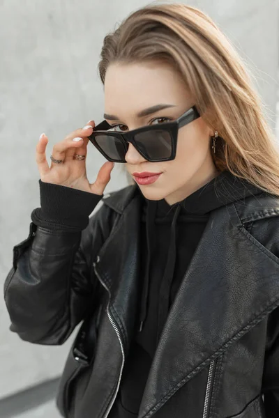 Modebewusste Hipsterin Mit Cooler Sonnenbrille Schwarzer Lederjacke Und Kapuzenpulli Blickt — Stockfoto