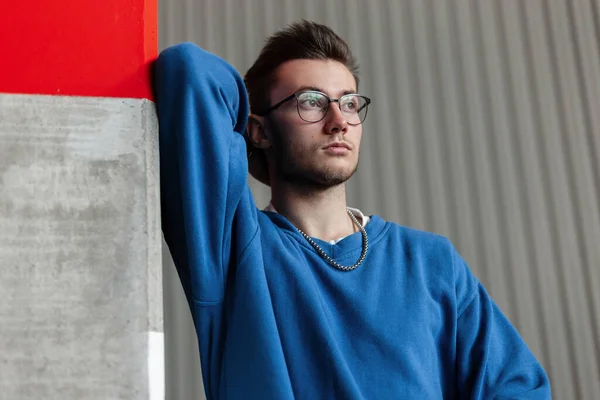 Handsome Hipster Man Blue Sweatshirt Glasses Stands Concrete Pole Street — Stock Photo, Image