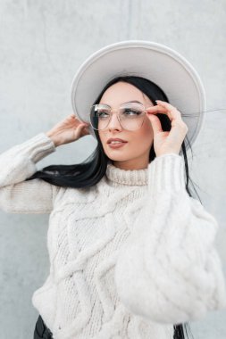 Moda örgü süveter giyen güzel bir genç kızın güzel bir portresi ve sokakta şık bir gözlük takıyor.