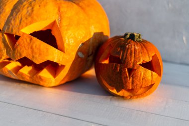 Mutlu Cadılar Bayramı. Korkunç turuncu Cadılar Bayramı balkabakları gün batımında beyaz ahşap bir arka planda. Sonbahar Hasadı.