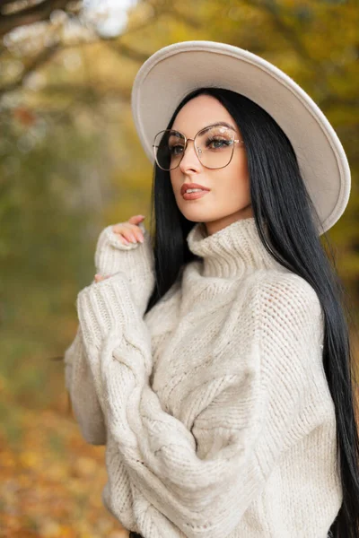 秋の肖像画の美しい女性でスタイリッシュな眼鏡でファッションニットセーターと白のエレガントな帽子の散歩色の秋の公園 — ストック写真