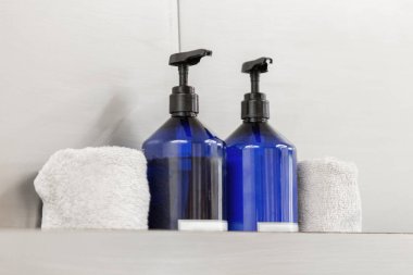 İki tane sabun ve antiseptik, bir güzellik stüdyosunun gri arka planında havlular.