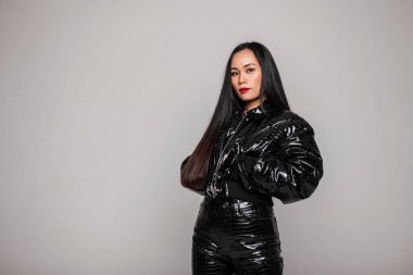 Stüdyoda gri arka planda ceketi ve pantolonu olan şık, siyah elbiseli, şık, genç Asyalı bir kadın. Kadın tarzı kıyafet ve güzellik.