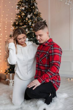 Güzel, genç, sevgi dolu mutlu çift Noel ağacı ve ışıklarıyla rahat moda kıyafetleri içinde. Tatiller, aile ve sigorta