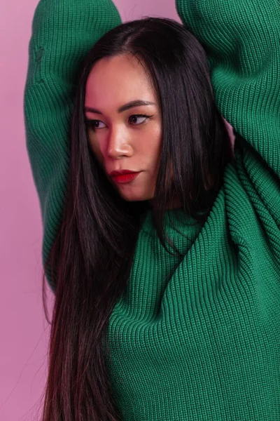 Stüdyoda yeşil örülmüş süveter ve pembe ışıkla süslenmiş güzel bir manken.