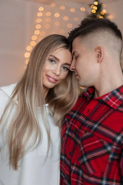 stock image Beautiful couple in love in fashion clothes at home near the Christmas tree and lights