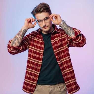 Moda kıyafetleri içindeki bir hipster 'ın stüdyo portresi yaratıcı ışıklandırmalı bir stüdyoda gözlük takıyor.