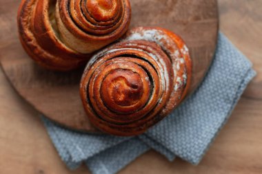 Tahta bir tahtanın üzerinde uzanan iki tatlı, lezzetli tarçın sincabı. Yeni pişmiş.