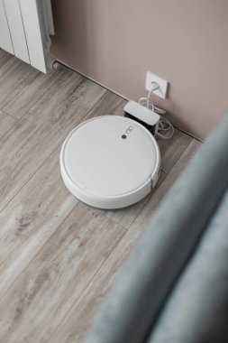 Akıllı beyaz robot süpürge odada şarj edildi.