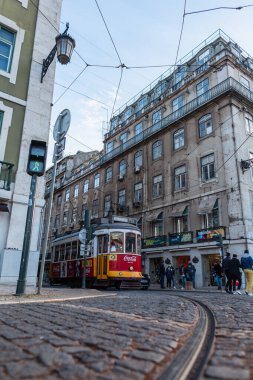Lizbon. Portekiz - 03 04 2022: Dar sokakları, yolu ve Coca Cola reklamlı kırmızı klasik tramvayı olan eski Lizbon kenti. Güzel binaları ve turistleri olan samimi Avrupa kasabası