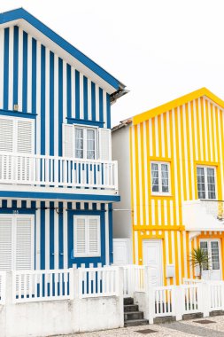 Portekiz 'de okyanus kıyısındaki bir tatil köyünde iki eski renkli çizgili kulübe. Daireler. Yaratıcı evler. Sarı ve mavi çizgili.