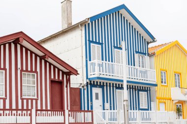 Portekiz 'de okyanus kıyısındaki bir tatil köyünde eski renkli çizgili kulübeler. Daireler. Yaratıcı evler. Kırmızı çizgili renkler.