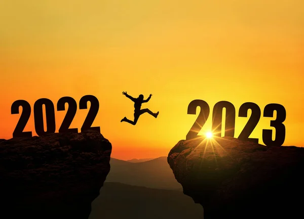 驚くべき日没で絶壁の上に2023崖の上にジャンプする男 新年のコンセプト 新年の始まりと歓迎の象徴2023年 創造的なアイデアが生まれます — ストック写真