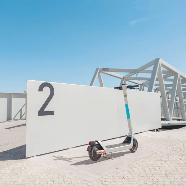 Electric scooter rental stands near the gray wall near the pier in sunny Portugal, Lisbon. Active and healthy transport