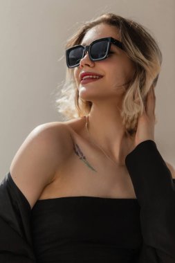 Happy Fashionable Women's Urban Portrait of a beautiful woman model with a smile and cool modern sunglasses in fashion black business clothes with a blazer and top in the city