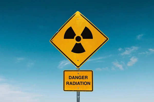 Yellow metal sign with radiation hazards against the blue sky. Danger zone and radioactive contamination