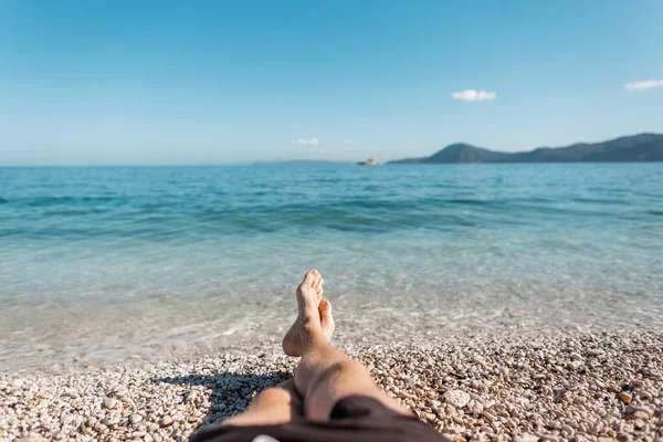 Successful man lies on the beach near the blue clear clean sea with sky on the island of Elba, Italy. Summer vacation and travel