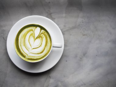 Yeşil çay fincanda ve akıllı telefon çalışma alanında.