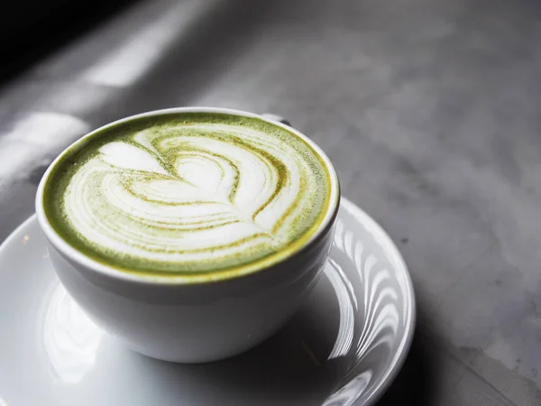 Yeşil çay fincanda ve akıllı telefon çalışma alanında.