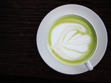 Sıcak yeşil çay fincanda ve kremalı beyaz yaprak. 