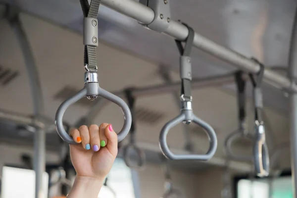 Gente aferrada a un asa en un tren — Foto de Stock