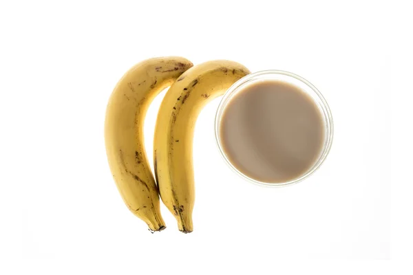 Due banane accanto a un bicchiere di latte isolato su sfondo bianco — Foto Stock