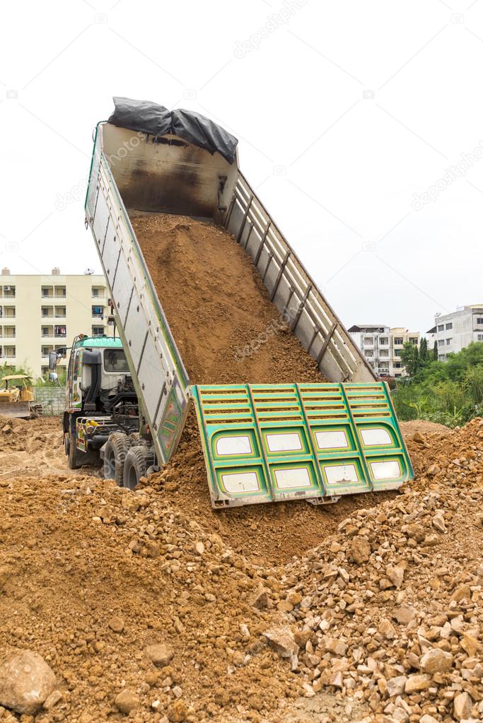 Dump truck dumps its load of rock and soil on land
