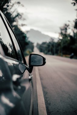 Arabanın dikiz aynasının görüntüsü. Arabanın yan tarafından yağmur damlaları alınmış..