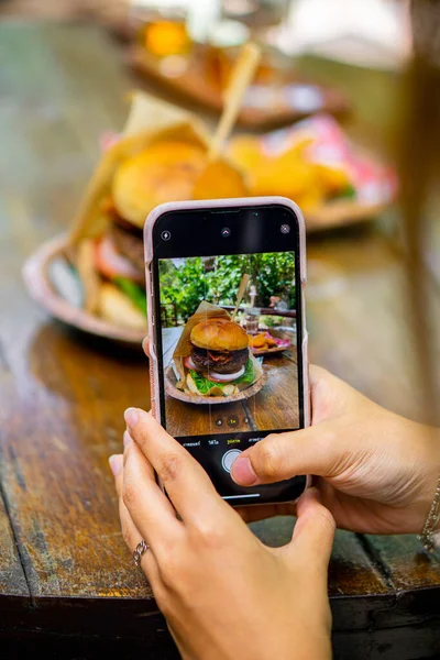 Woman Taking Picture Burger Her Smartphone — Fotografia de Stock