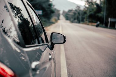 Arabanın dikiz aynasının görüntüsü. Arabanın yan tarafından yağmur damlaları alınmış..