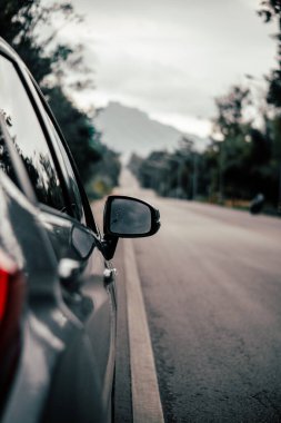 Arabanın dikiz aynasının görüntüsü. Arabanın yan tarafından yağmur damlaları alınmış..