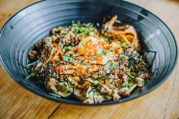 Kore Onsen yumurtalı eriştesi, siyah tabakta, ahşap bir masada, yakın plan.