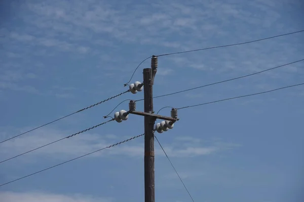 Simple rural electricity distribution pylon and power lines under blue sky