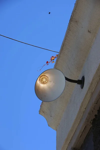 Освещённая Электрическая Лампа Углу Здания Кабель Веточка Разноцветными Опадающими Листьями — стоковое фото
