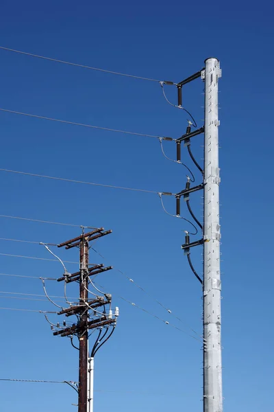 Zwei Verschiedene Stromverteilungsmasten Mit Stromleitungen Unter Blauem Himmel — Stockfoto