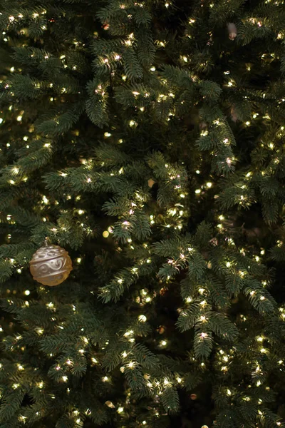 Dílčí Pohled Umělý Vánoční Stromek Jednou Zlatou Ornamentální Koulí Ozářený — Stock fotografie