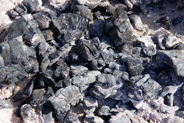 ビーチの放棄された火の穴で焼かれた木炭のクローズアップビュー — ストック写真