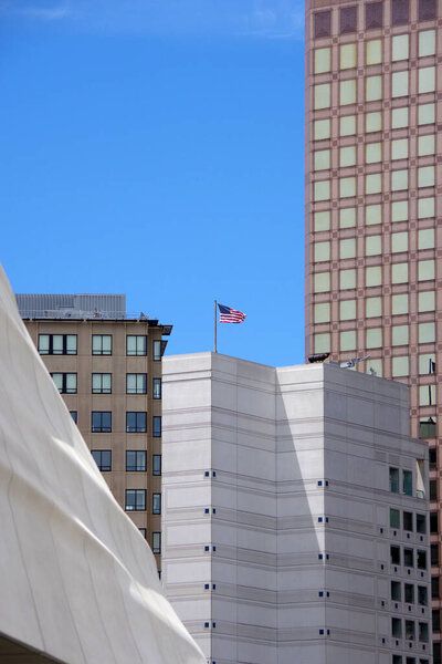 Skyscraper in the city under bright blue sky  one of them with a US flag on top