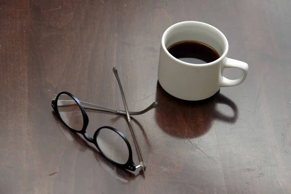 Una Taza Café Medio Lleno Anteojos Una Mesa Madera —  Fotos de Stock