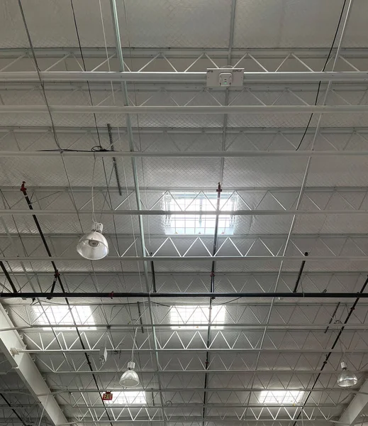 Inside ceiling structure of a warehouse with skylights and also electric lighting