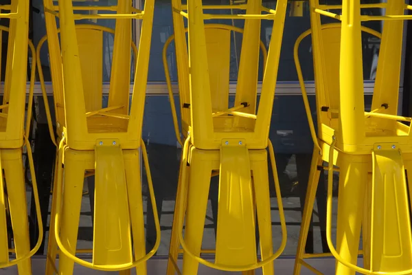 Stacked yellow metal bar stool chairs