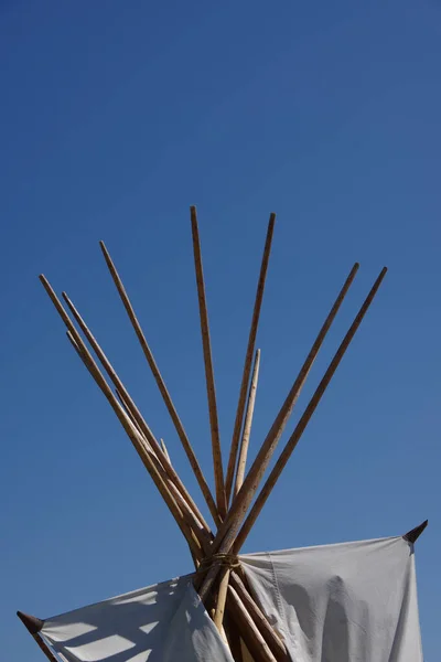 The wooden poles at the top of a tipi aka. teepee under blue sky