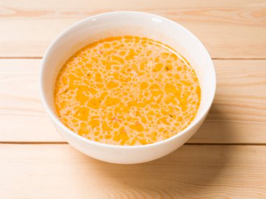 Tahta arka planda beyaz yuvarlak tabakta peynir çorbası. Yukarıdan görüntüle