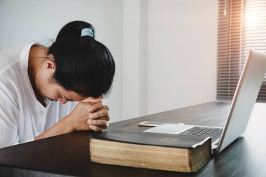 Kadın kız evde kalır ve diz üstü bilgisayarla Tanrı 'ya dua eder. Dua eden kızlar Coronavirus krizi için dua ederler. Ev kilisesi, çevrimiçi kilise, dua eden eller, evde ibadet