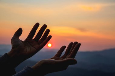 Günbatımı arka planında siluet kadın. İbadet ederken ellerini kaldıran bir kadın. Hıristiyan Dini kavramı arka planı.