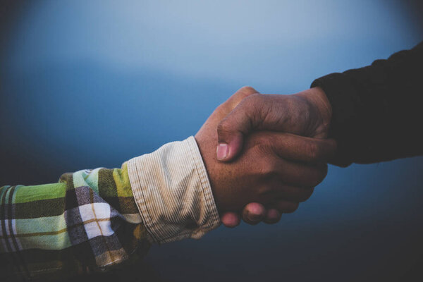 Help Concept hands reaching out to help each other in dark tone.