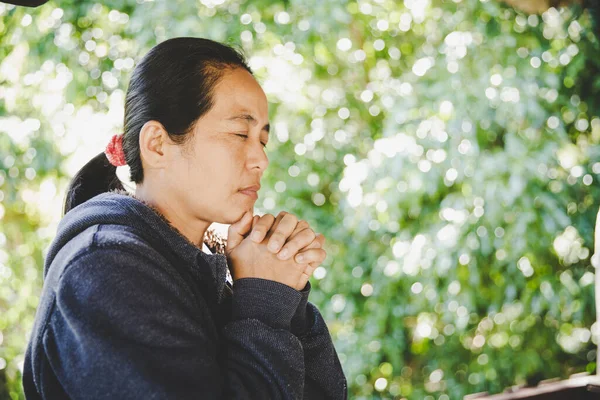 portrait of a young woman praying in nature, the girl thanks God with her hands folded at her chin, a conversation with the Creator, the concept of religion