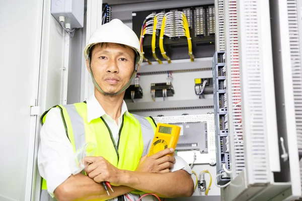 handsome electrical engineer arms crossed and current of power electric line in electrical cabinet control.