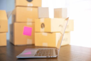 İş yerinde dizüstü bilgisayar var. Çevrimiçi satış, e-ticaret, paketleme konsepti, sabah ışığı